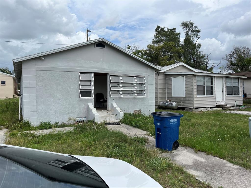A gray concrete block house with jalousie windows sits next to a light-colored siding home — 852 SHIRLEY STREET, SEBRING, FL