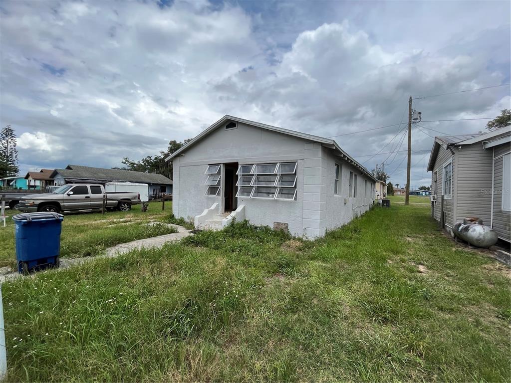 A single-story, light gray house with a front entrance and jalousie windows sits on grass — 852 SHIRLEY STREET, SEBRING, FL