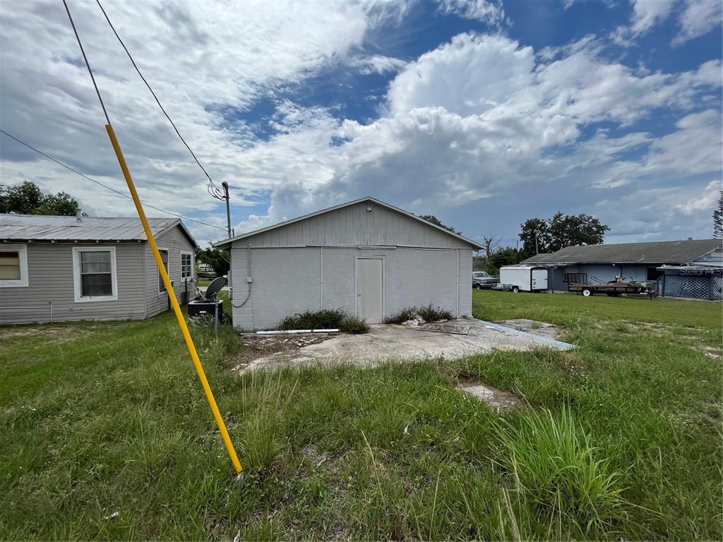 A detached, light-colored storage building sits on a concrete pad in a grassy yard — 852 SHIRLEY STREET, SEBRING, FL