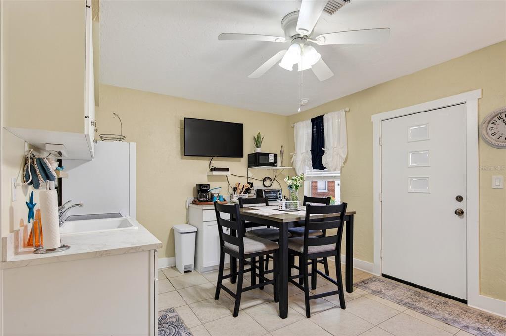 A kitchen and dining area with a table, four chairs, a television, and white cabinets — 908 VILLAS DRIVE UNIT 29, VENICE, FL