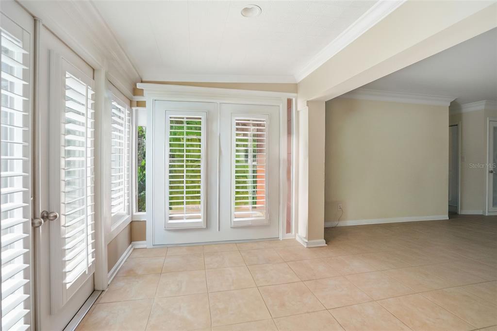 A sunroom features tile flooring, white plantation shutters on the doors and windows, and crown molding — 10002 DOMINGO DRIVE, BROOKSVILLE, FL