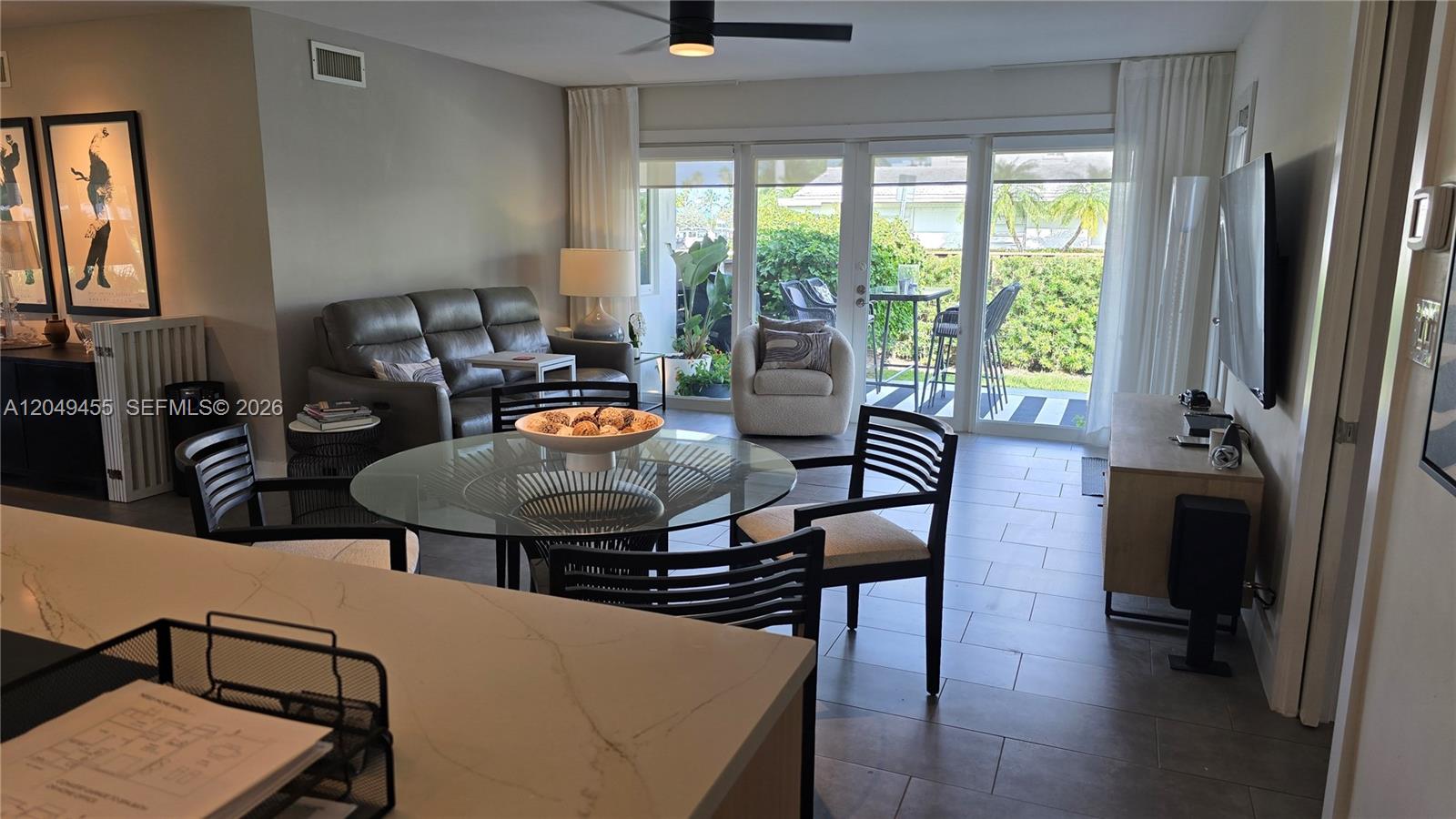A living and dining area features a glass table, gray sofa, and sliding glass doors — 800 Polk St, Hollywood FL 33019, HOLLYWOOD, FL