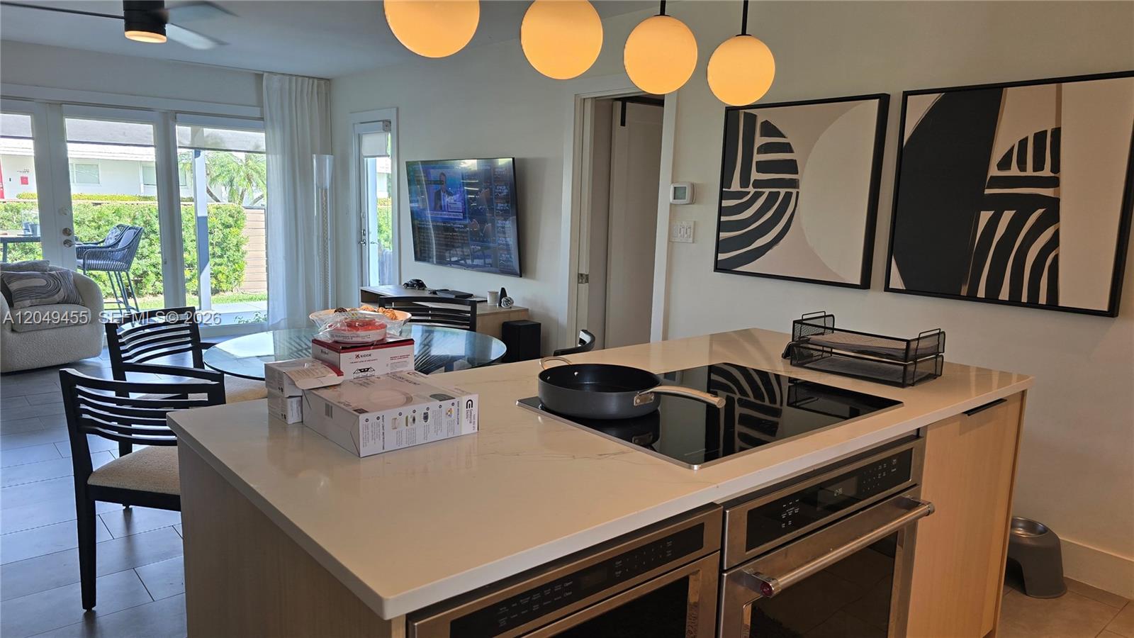 A kitchen island with a cooktop and oven sits in a room with modern decor — 800 Polk St, Hollywood FL 33019, HOLLYWOOD, FL