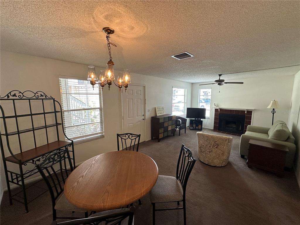 A dining area with a wooden table and metal chairs opens into a carpeted living room — 3646 59TH AVENUE W UNIT 3646, BRADENTON, FL