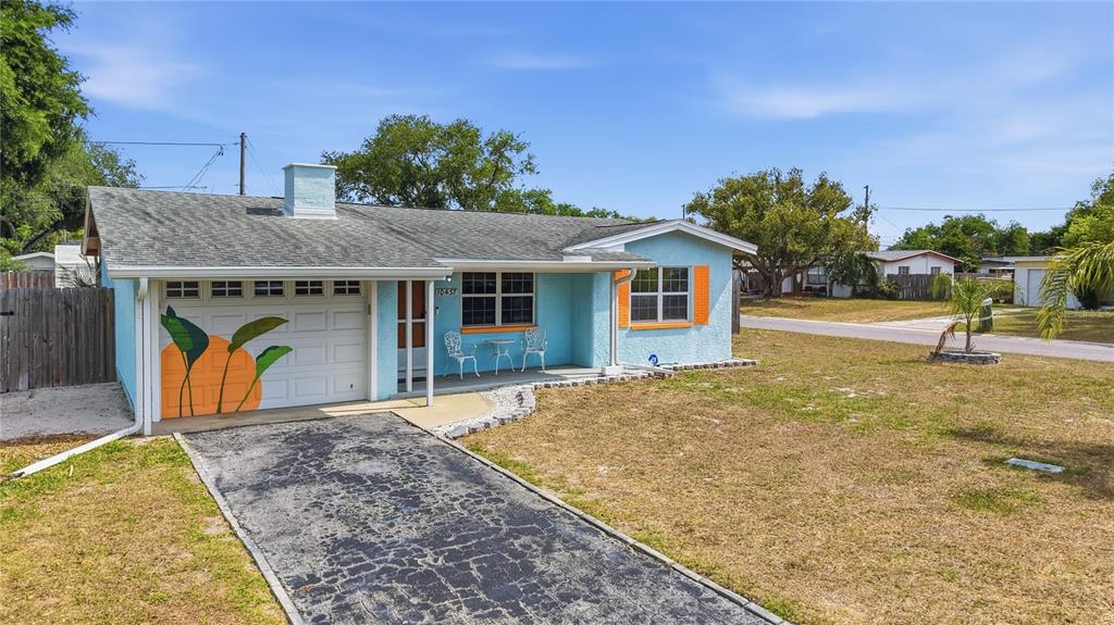 A light blue house with an orange-painted garage door and a paved driveway — 10437 52ND AVENUE N, ST PETERSBURG, FL