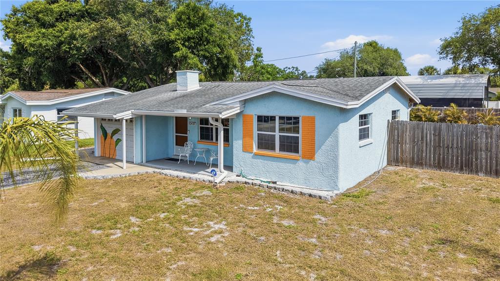 A light blue single-story house with orange shutters, a covered porch, and a gravel driveway — 10437 52ND AVENUE N, ST PETERSBURG, FL