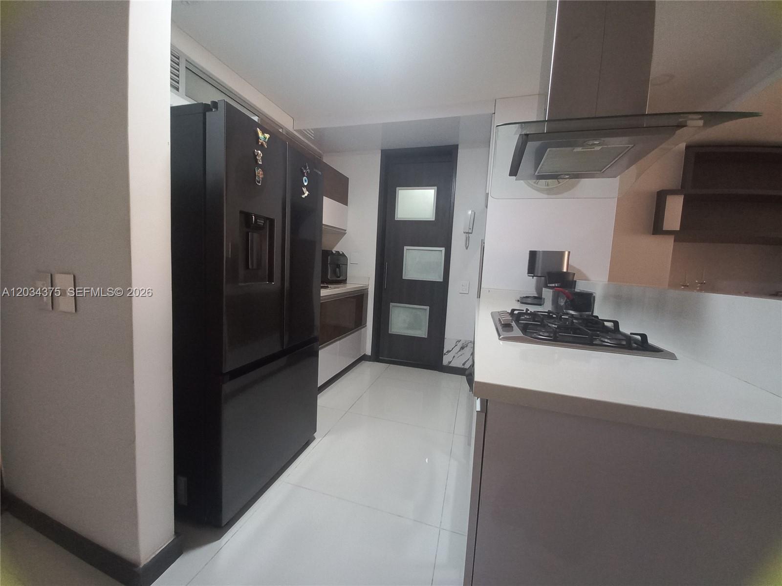 A modern kitchen features a black refrigerator, white countertops, a gas cooktop, and tile flooring — Cra. 19 # 9 - 110 # 101, FL, FL