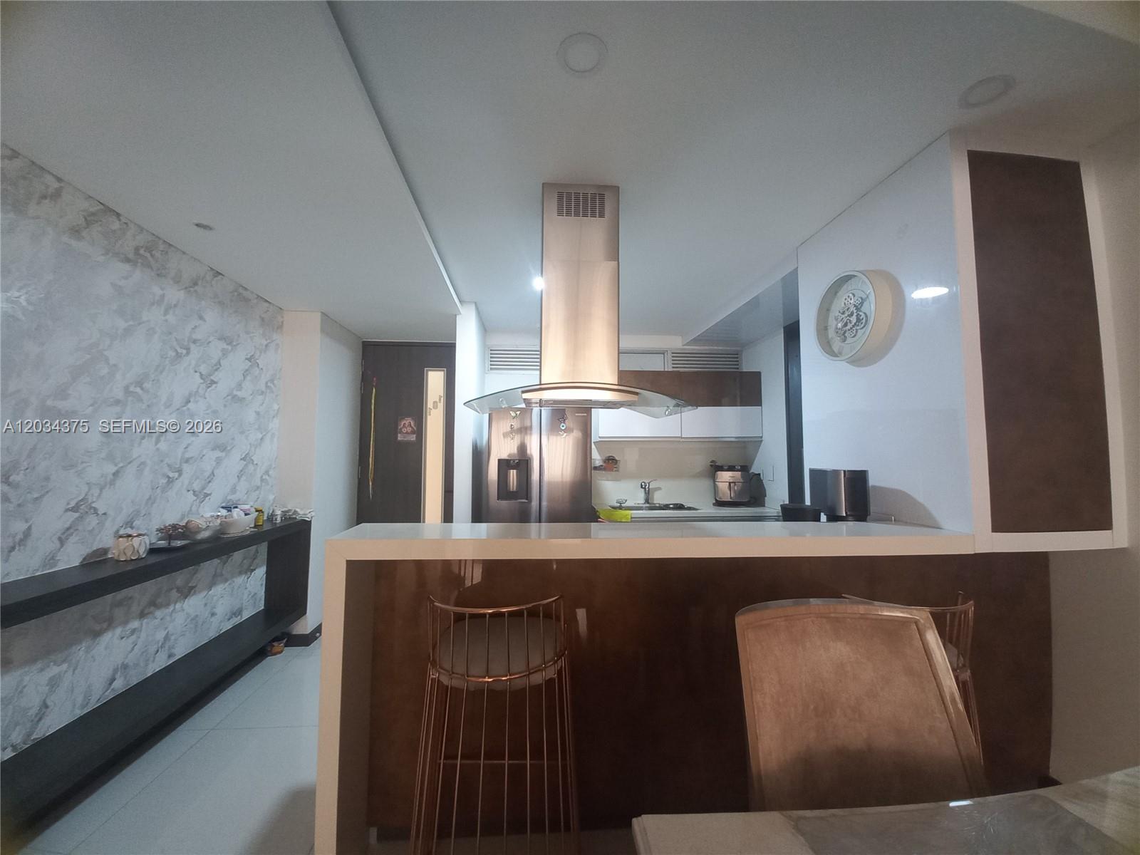 A modern kitchen features a stainless steel range hood, a breakfast bar, and marble-patterned walls — Cra. 19 # 9 - 110 # 101, FL, FL
