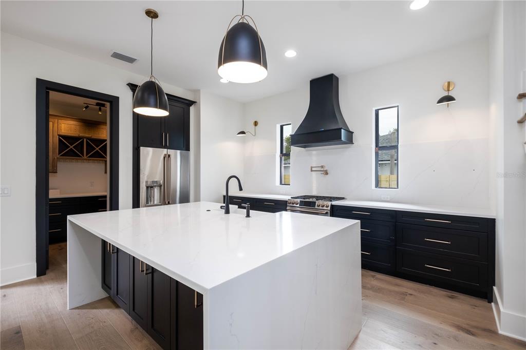 A modern kitchen features black cabinets, a large white waterfall island, and stainless steel appliances — 818 W KENTUCKY AVENUE, TAMPA, FL
