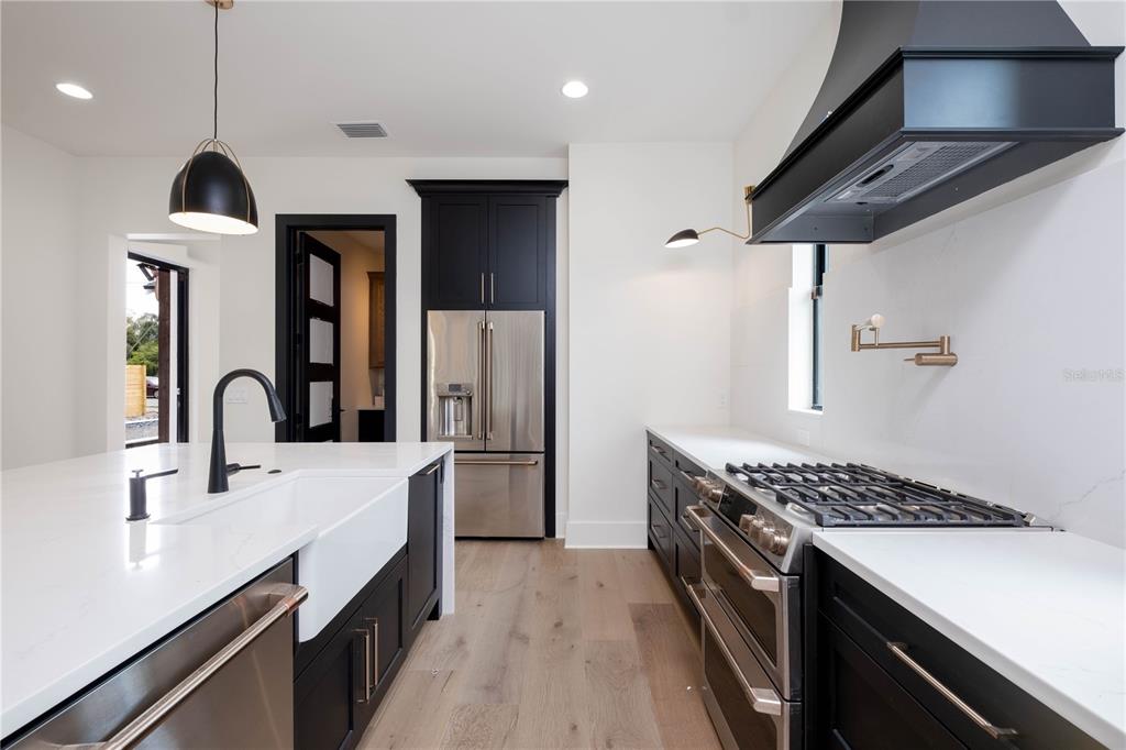 A modern kitchen features black cabinetry, stainless steel appliances, a farmhouse sink, and white countertops — 818 W KENTUCKY AVENUE, TAMPA, FL