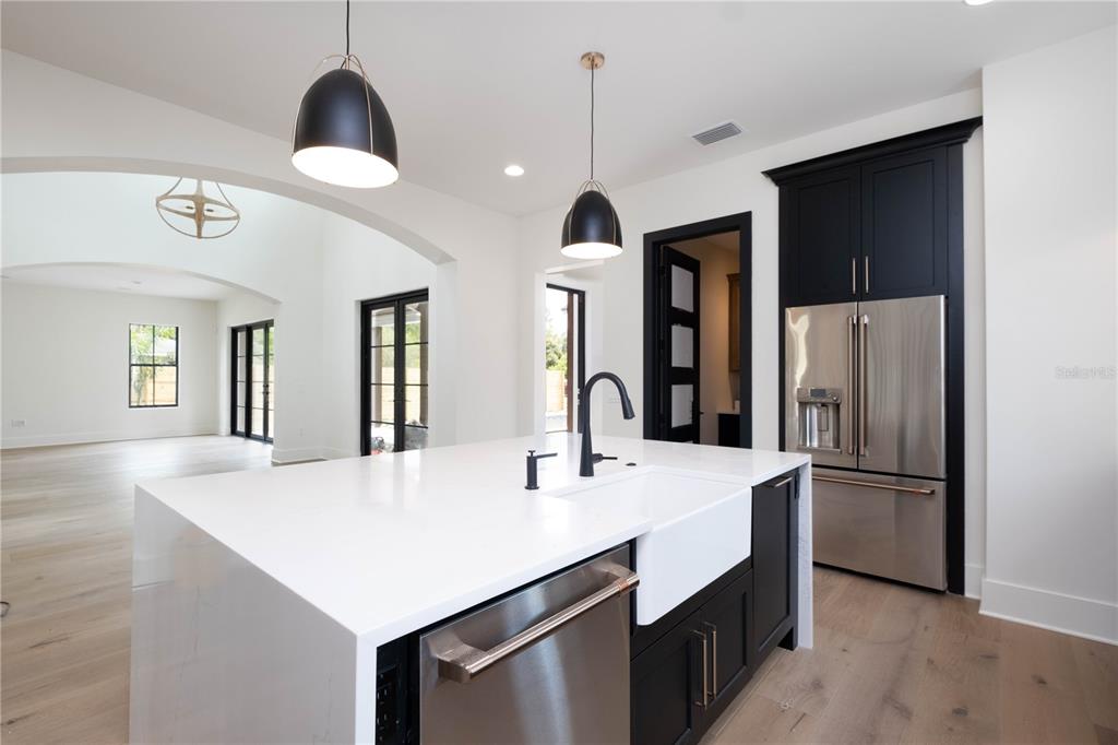 A modern kitchen features a white quartz island with a farmhouse sink and black cabinetry — 818 W KENTUCKY AVENUE, TAMPA, FL