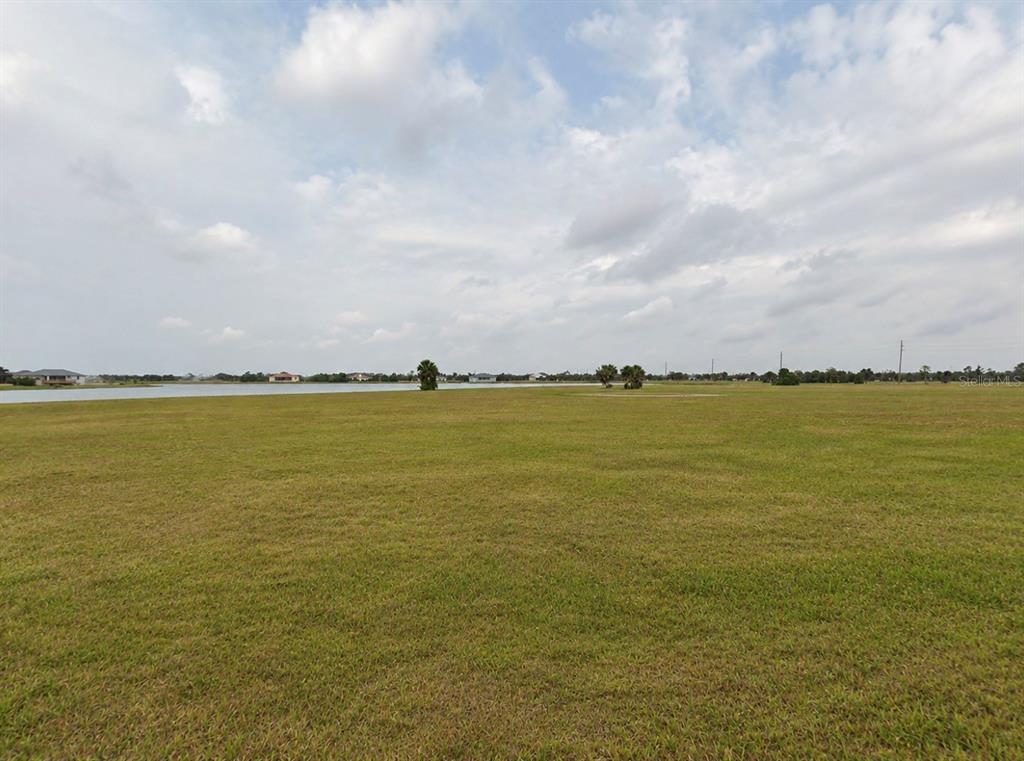 A large, flat, grassy vacant lot overlooks a lake under a cloudy sky — 5 TEAK LANE, PLACIDA, FL