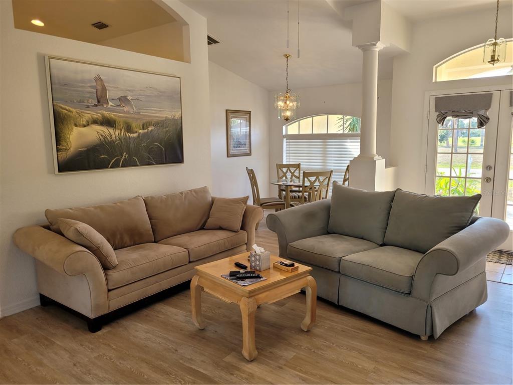 A living room with two sofas, a coffee table, and a dining area in the background — 72 LONG MEADOW COURT, ROTONDA WEST, FL