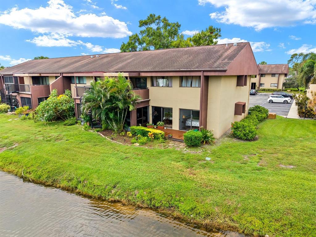 An exterior view of a two-story apartment building situated along a small canal — 875 S VILLAGE DRIVE N UNIT 101, ST PETERSBURG, FL