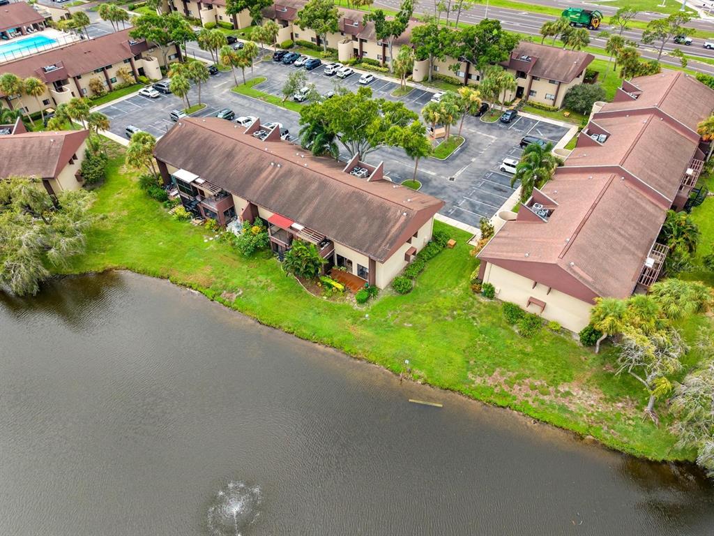 An aerial view of a multi-story apartment complex situated next to a pond — 875 S VILLAGE DRIVE N UNIT 101, ST PETERSBURG, FL