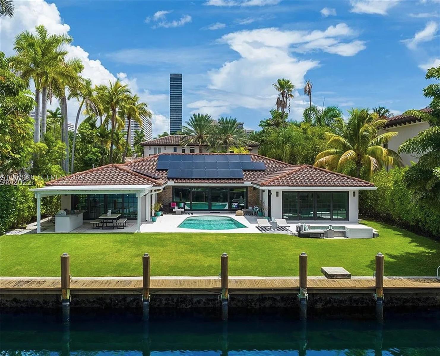 A waterfront house with a swimming pool, solar panels, and a wooden dock — 524 Oleander Dr, Hallandale Beach FL 33009, HALLANDALE BEACH, FL