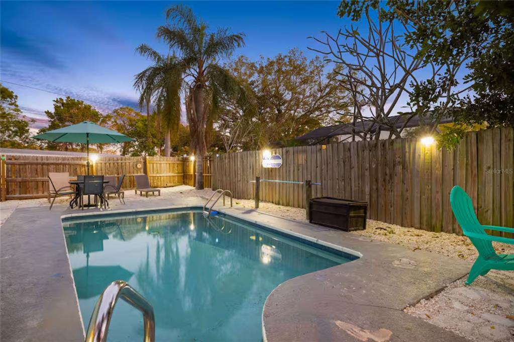 A backyard swimming pool with a patio, outdoor furniture, and a wooden privacy fence — 201 SOUTH STREET, PALM HARBOR, FL