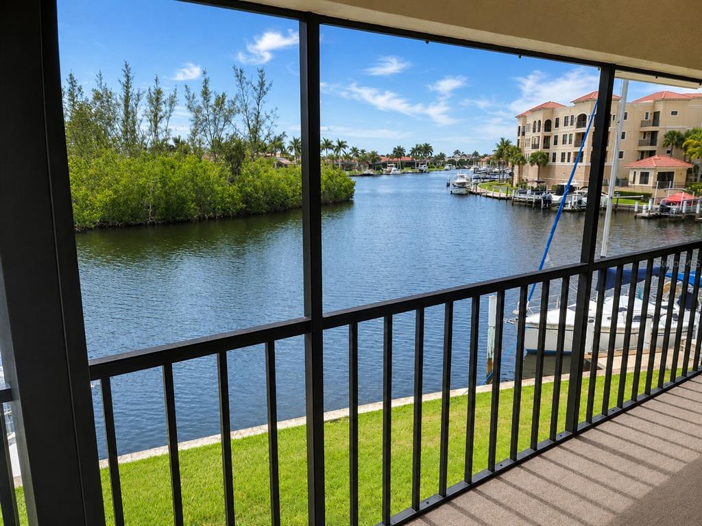 A screened-in balcony overlooks a canal with boats and residential buildings in the distance — 3256 WHITE IBIS COURT UNIT 325, PUNTA GORDA, FL