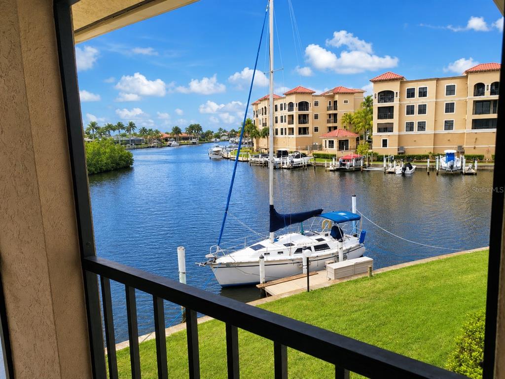 A view from a balcony overlooking a canal with a sailboat and apartment buildings — 3256 WHITE IBIS COURT UNIT 325, PUNTA GORDA, FL