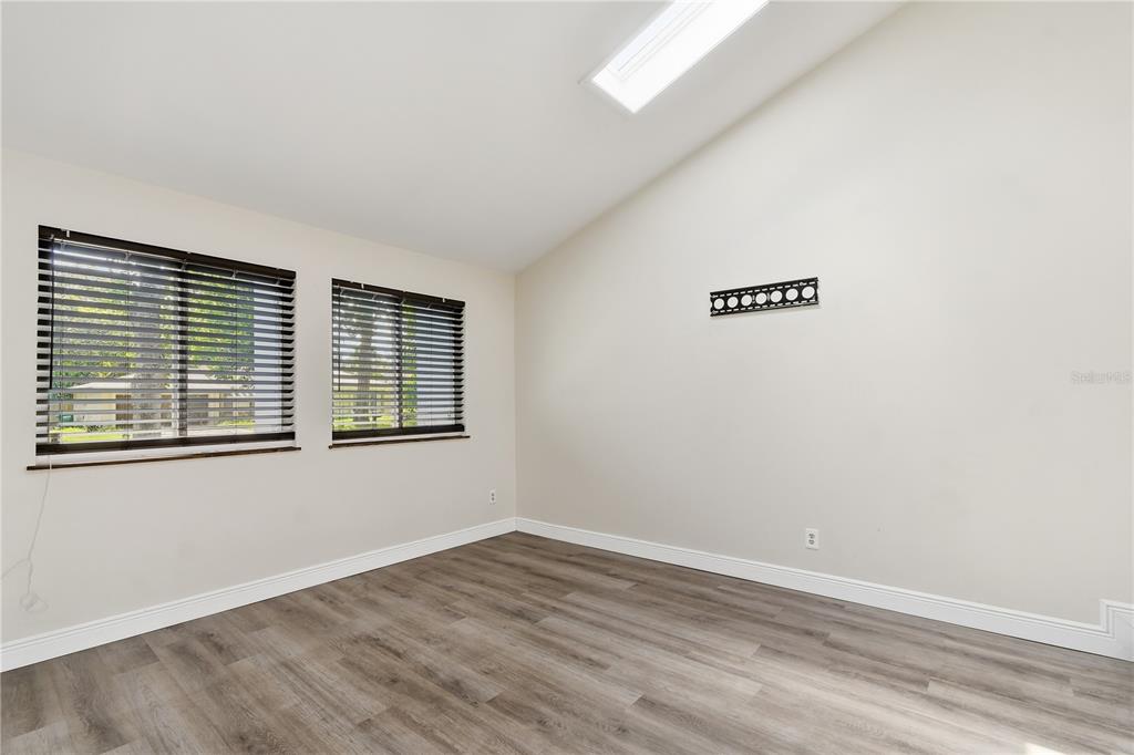 An empty room with wood-look flooring, two windows with blinds, and a wall-mounted television bracket — 758 N GRETNA COURT, WINTER SPRINGS, FL
