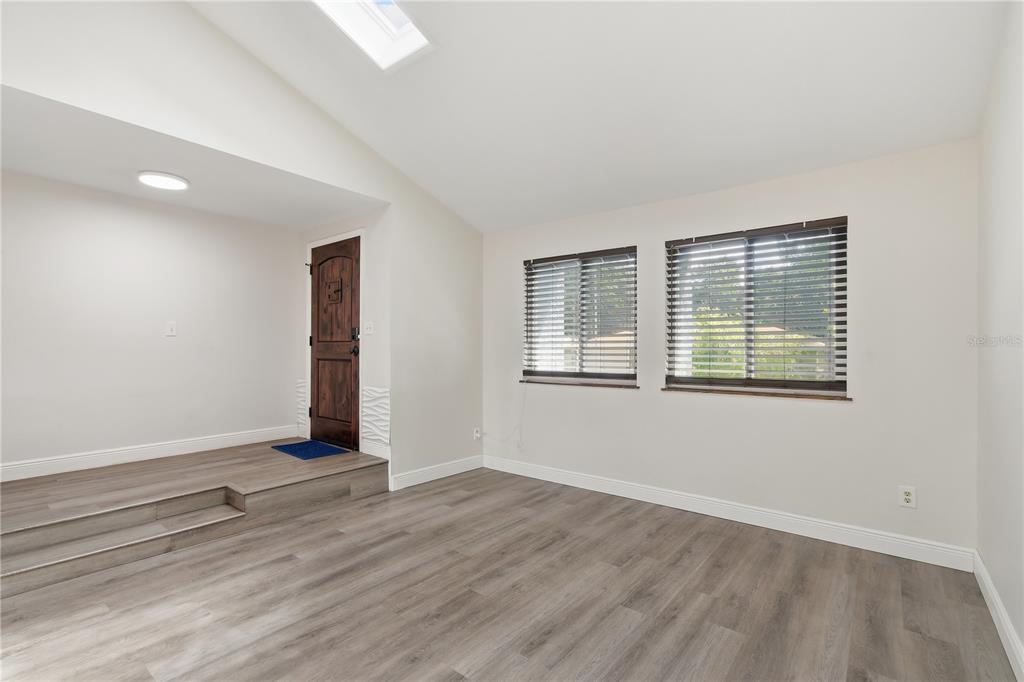 A living room with light wood-look flooring, a raised entryway, and two windows with blinds — 758 N GRETNA COURT, WINTER SPRINGS, FL