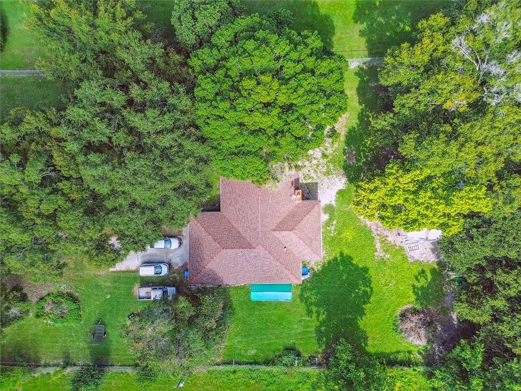 An aerial view shows a house with a brown roof surrounded by trees and grass — 18139 BENES ROUSH ROAD, BROOKSVILLE, FL