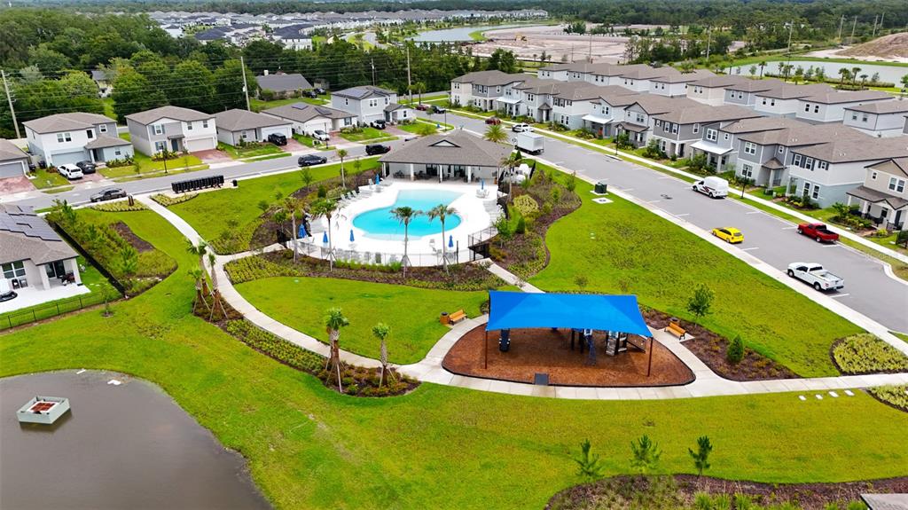 An aerial view shows a suburban neighborhood with a community swimming pool and playground area — 4630 HOMESTEAD TRAIL, ST CLOUD, FL