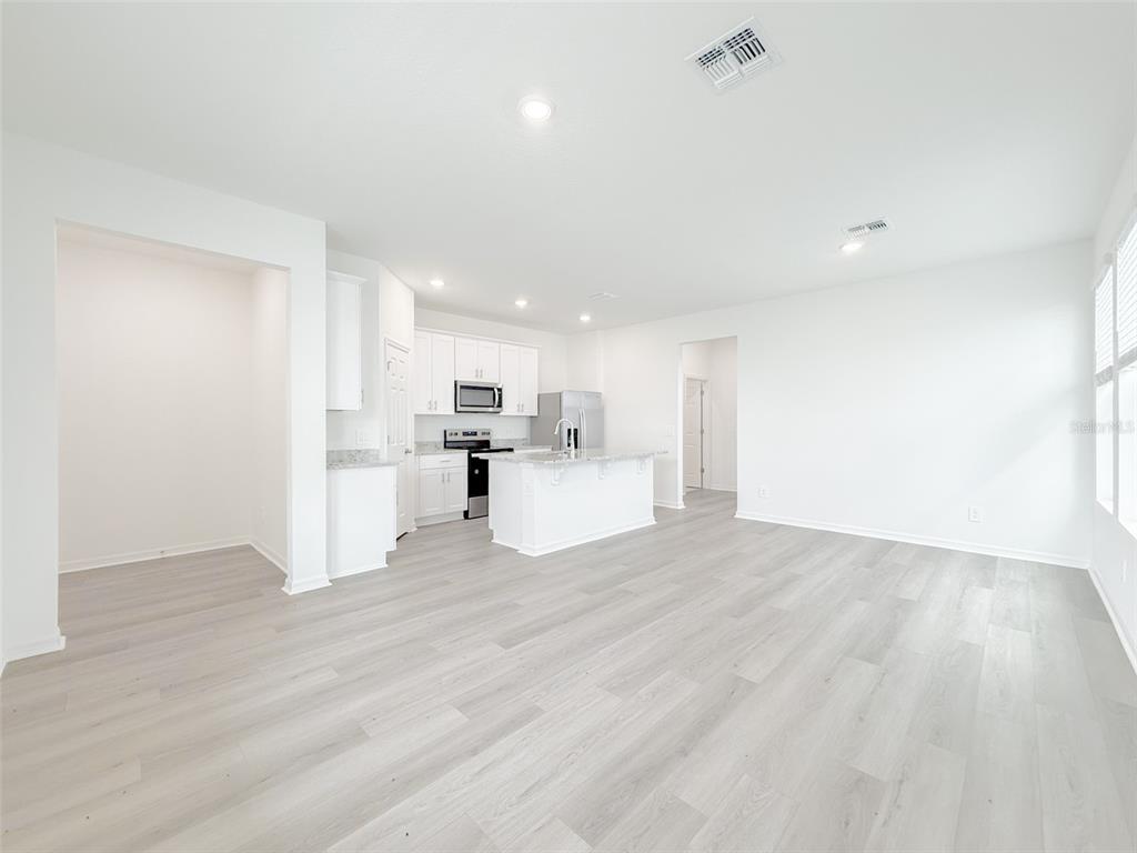 An open-concept kitchen and living area features white cabinetry, a center island, and light flooring — 4630 HOMESTEAD TRAIL, ST CLOUD, FL