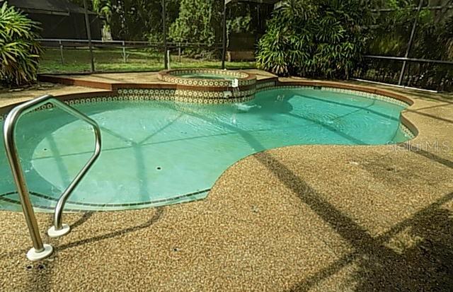 A swimming pool with an attached spa is enclosed within a screened-in patio area — 3972 HELENE STREET, SARASOTA, FL