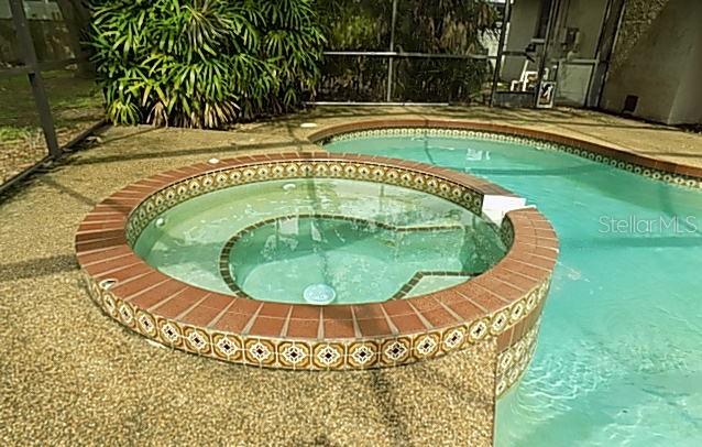 A circular hot tub with decorative tile trim sits adjacent to a swimming pool — 3972 HELENE STREET, SARASOTA, FL