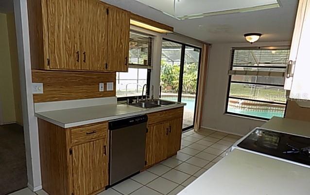 A kitchen with wood cabinets, a stainless steel dishwasher, and a view of a pool — 3972 HELENE STREET, SARASOTA, FL