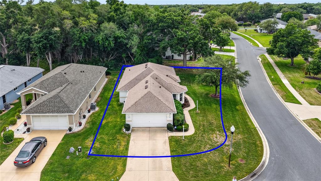 An aerial view shows a single-story house with a tan roof and a concrete driveway — 27545 DISCOVER COURT, LEESBURG, FL