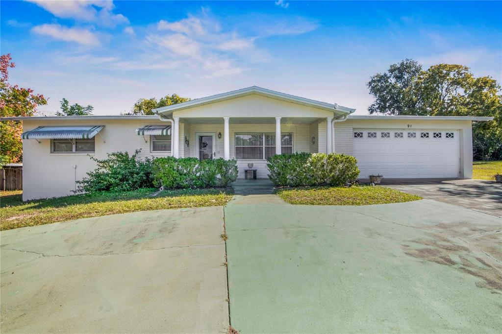 A single-story house with a white brick facade, a covered porch, and a two-car garage — 91 S LEE STREET, BEVERLY HILLS, FL