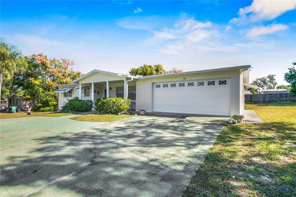 A single-story house with a white brick exterior, a two-car garage, and a concrete driveway — 91 S LEE STREET, BEVERLY HILLS, FL