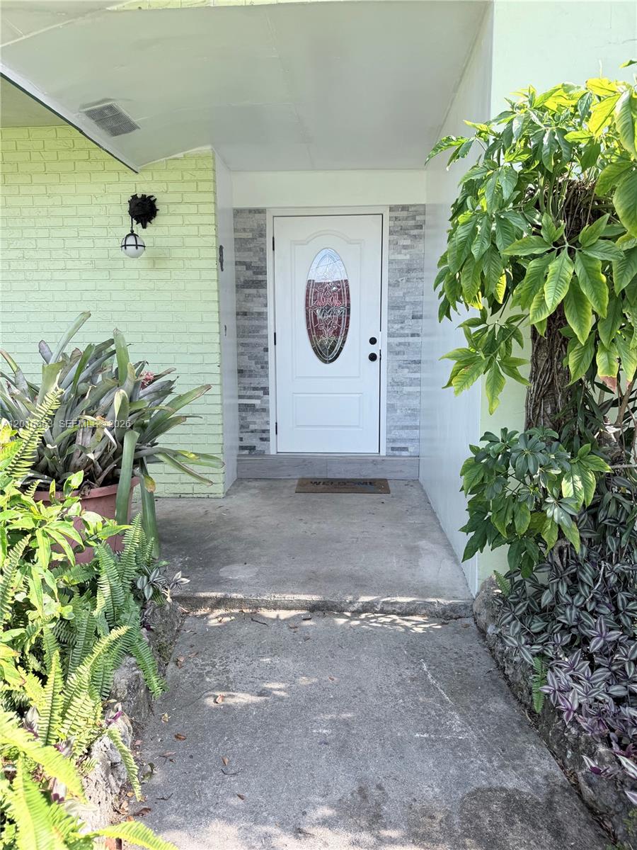 The front entrance features a white door with a decorative oval window and stone siding — 4420 NW 16th St, Lauderhill FL 33313, LAUDERHILL, FL