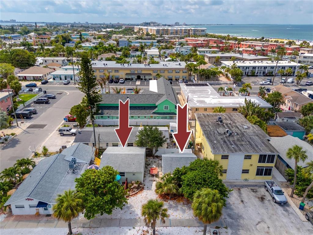 An aerial view shows two small, adjacent residential buildings with white roofs and surrounding trees — 610 72ND AVENUE, ST PETE BEACH, FL