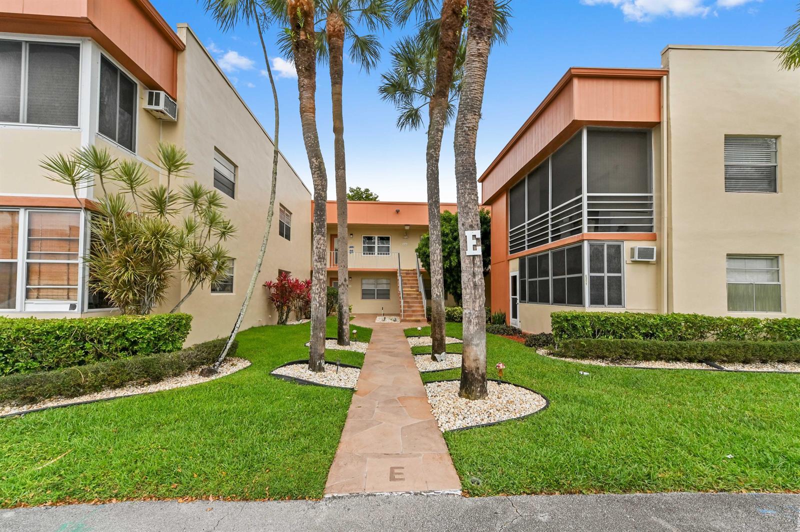 A stone walkway leads between two apartment buildings with palm trees and manicured lawns — 211 Piedmont E, Delray Beach FL 33484, DELRAY BEACH, FL