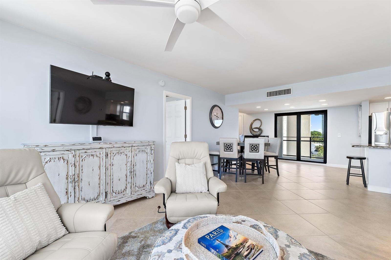 A living and dining area features light-colored tile floors, leather armchairs, and a balcony view — 336 Golfview Road # 619, North Palm Beach FL 33408, NORTH PALM BEACH, FL