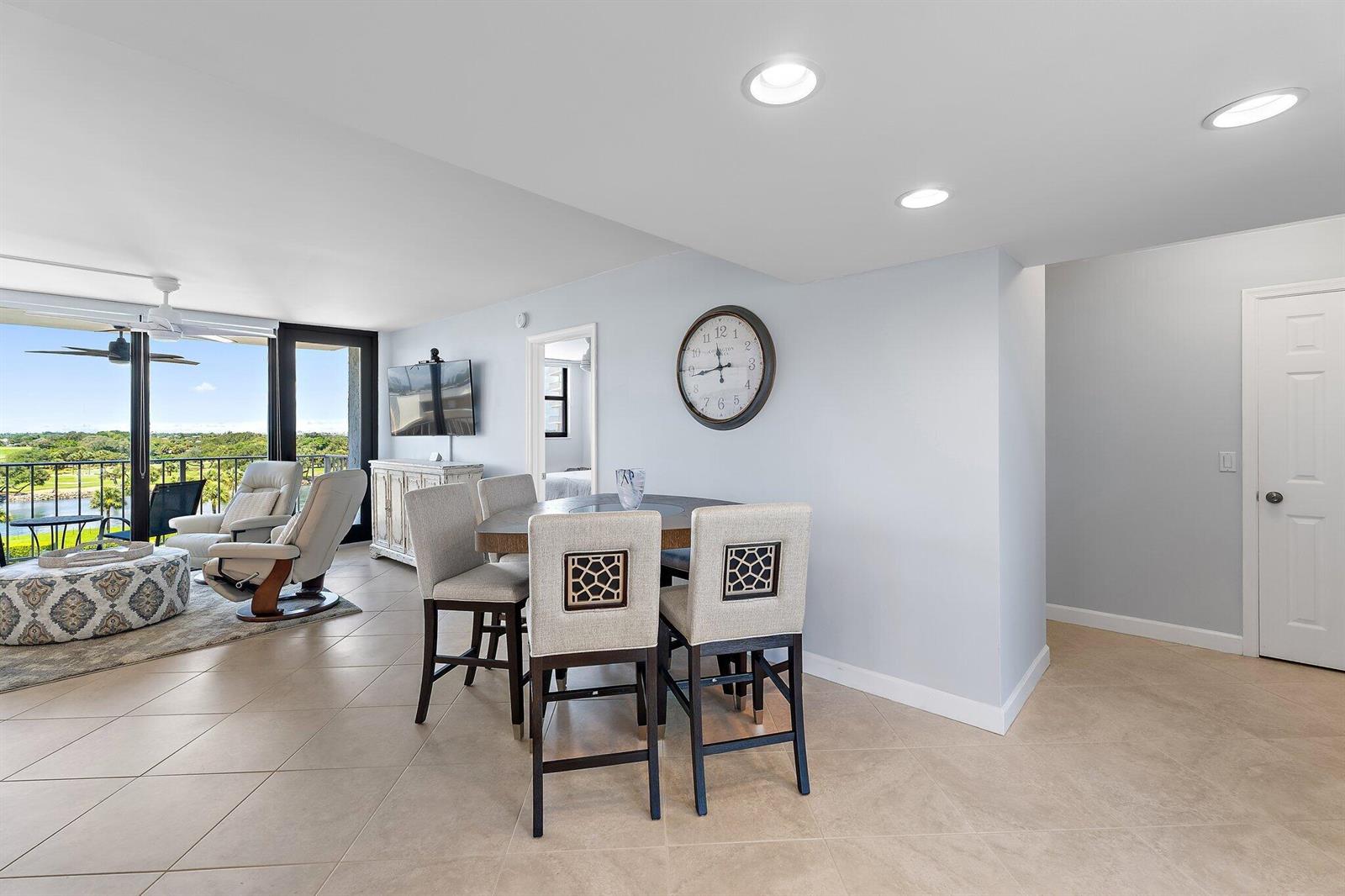 A dining area with four chairs sits next to a living room overlooking a golf course — 336 Golfview Road # 619, North Palm Beach FL 33408, NORTH PALM BEACH, FL