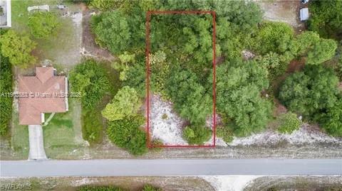 An aerial view shows a rectangular, wooded vacant lot outlined in red next to a house — 2514 38TH ST, Lehigh Acres FL 33971, LEHIGH ACRES, FL