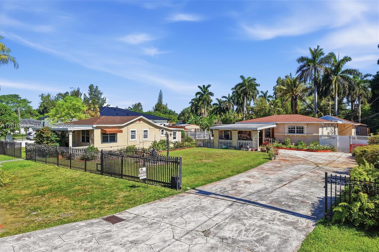 Two single-story houses with driveways and lawns are enclosed by a black metal fence — 55-57 NE 156th St, Miami FL 33162, MIAMI, FL