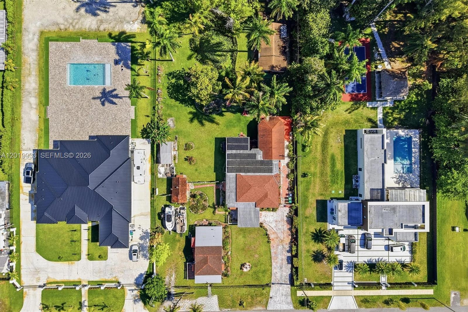 Aerial view of three residential properties featuring swimming pools, a pickleball court, and lush landscaping — 55-57 NE 156th St, Miami FL 33162, MIAMI, FL