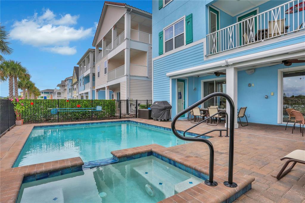A backyard swimming pool and hot tub sit on a paved patio beside a house — 3056 PARROT HEAD PLACE, KISSIMMEE, FL