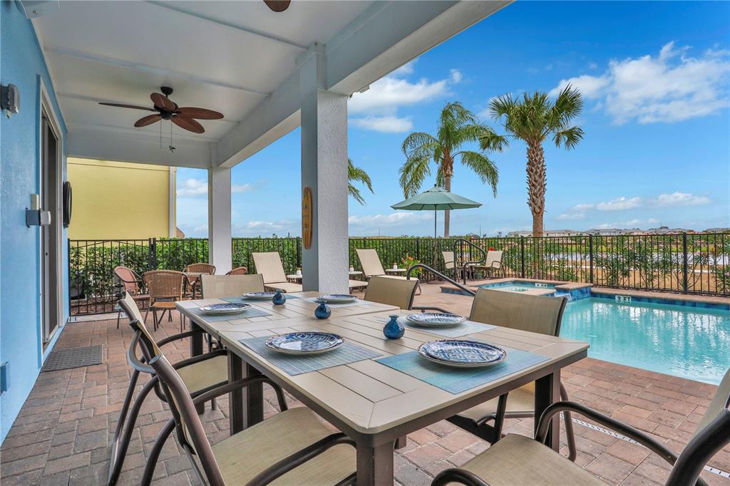 A covered patio features a dining set, a swimming pool, and a view of palm trees — 3056 PARROT HEAD PLACE, KISSIMMEE, FL