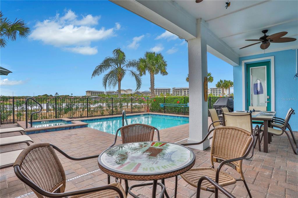 A covered patio features a pool, hot tub, and outdoor dining area overlooking a lake — 3056 PARROT HEAD PLACE, KISSIMMEE, FL