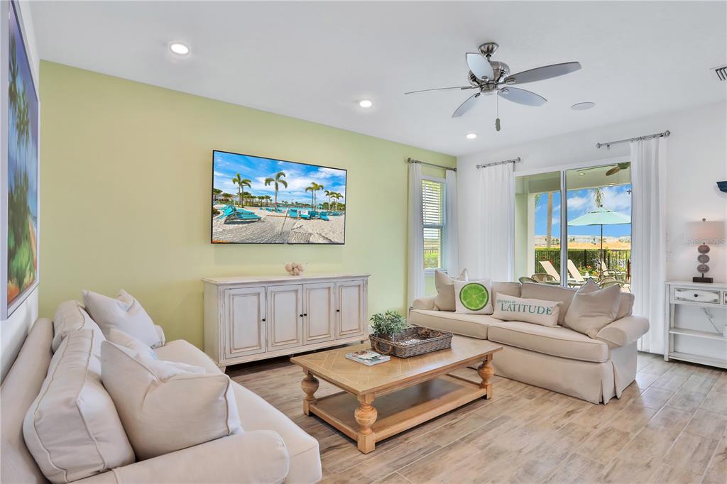 A living room features light green walls, two beige sofas, a wooden coffee table, and television — 3056 PARROT HEAD PLACE, KISSIMMEE, FL