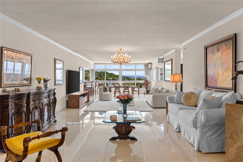 A spacious living room features tile flooring, a crystal chandelier, and large windows with views — 14 CARR 833 UNIT 1404, GUAYNABO, PR