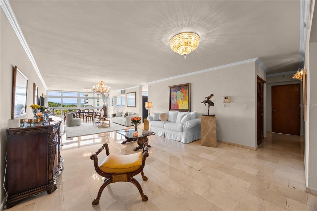 A spacious living room features marble floors, a crystal chandelier, and a view of the ocean — 14 CARR 833 UNIT 1404, GUAYNABO, PR