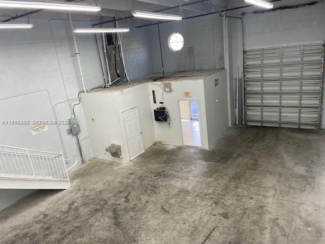 An industrial warehouse space features a concrete floor, a metal staircase, and a roll-up door — 13860 SW 143rd Ct # 2, Miami FL 33186, MIAMI, FL