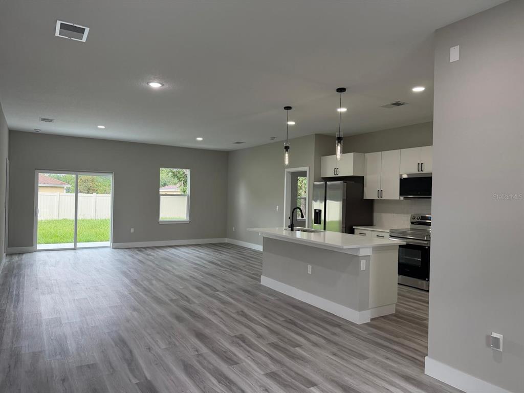 A modern kitchen features white cabinetry, quartz countertops, a center island, and stainless steel appliances — 7980 N PITCAIRN WAY, CITRUS SPRINGS, FL